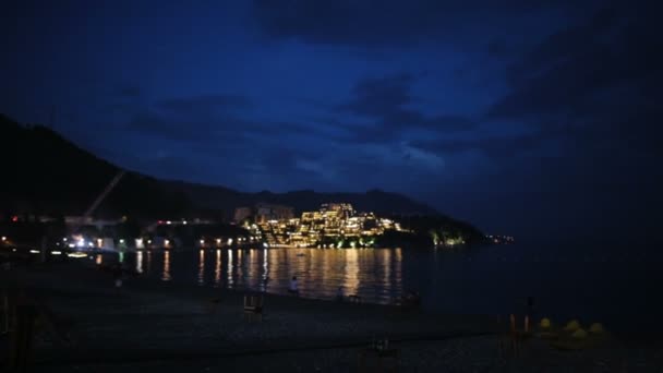 View of the night beach in tourist resort town Budva in the evening, beautiful landscape with the sea and island in Montenegro like a Italy or Croatia — Stock Video