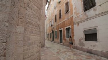 Turist kız eski ortaçağ şehir veya şehir bir İtalya ve Hırvatistan gibi Karadağ'ın dar Arnavut kaldırımlı cadde boyunca yürüyüş