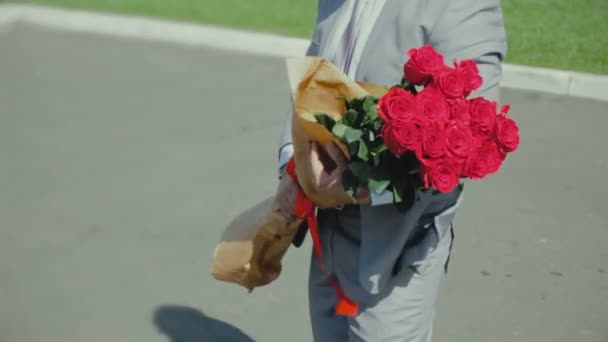 Чоловік з букетом троянд чекає на дівчину, романтичне або перше побачення, пропозиція про шлюб — стокове відео