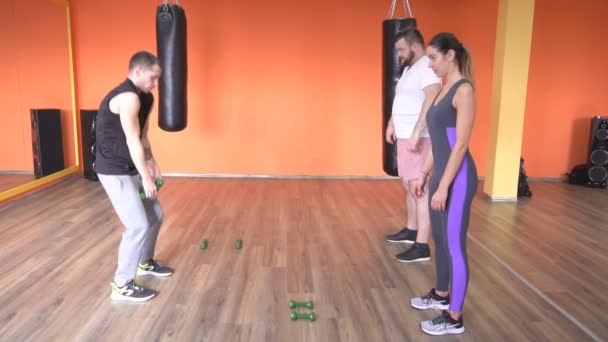 Mężczyzna trener sztuk walki uczy mężczyznę i dziewczynę do wykonywania bezpośrednich ćwiczeń hantle, powolny mo, profesjonalne — Wideo stockowe