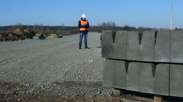 Földmérő vagy vezető néz ki, és írja információk szegélyek, útépítési nehéz építőipari berendezések előtt — Stock videók