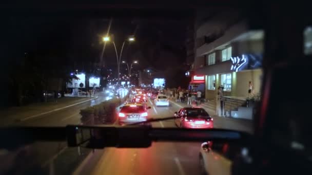 Переглянути через автобус лобове скло, яке їздити на дорозі ніч вулиці в туристичних курортне містечко — стокове відео