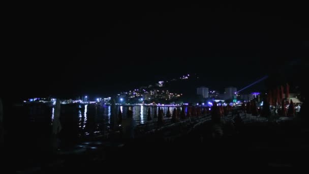 Natt strand med solstolar i turist utväg stad eller Budva stad på natten, vackra landskap med ljusreflektioner i havet i Montenegro som en Italien eller Kroatien — Stockvideo