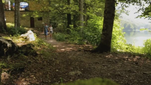 Młoda para turyści chodzą w lesie lasów w pobliżu jeziora w lecie — Wideo stockowe