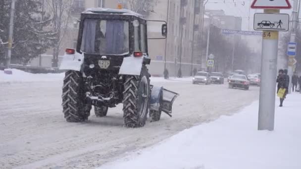 Bobruisk, Fehéroroszország - 2019. január 14.: Egy régi traktor hóeltakarítás túrák, a téli város, havazás, lassú mozgás — Stock videók