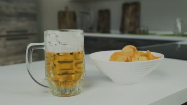 Szkło kubek kufel pilsener lub piwo lager z chipsy są w kuchni — Wideo stockowe