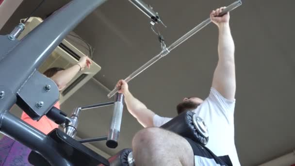 Hombre gordo con barba se dedica al gimnasio en el impulso de ejercicio simulador con el instructor de chica, estilo de vida, ropa deportiva — Vídeos de Stock