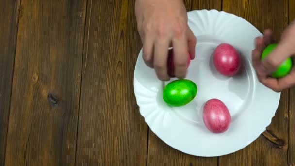 O homem põe em uma chapa os ovos coloridos tingidos e pintados de Easter durante um Domingo de Páscoa ou Ressurreição — Vídeo de Stock