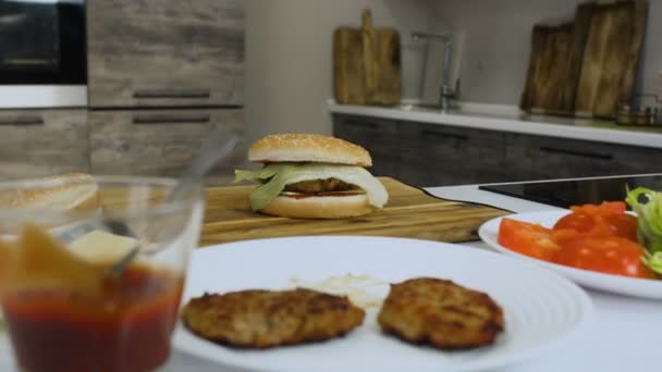 Cocinado hamburguesa casera está en una mesa en una cocina moderna — Vídeos de Stock