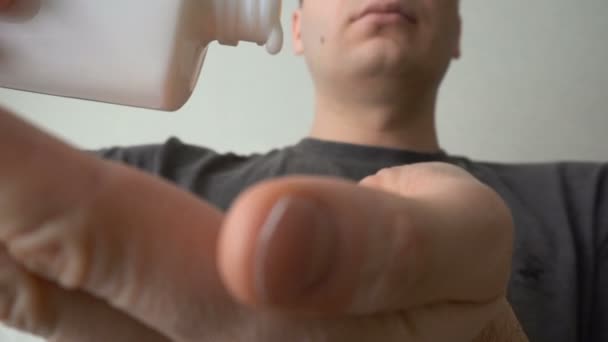 Closeup man giet op zijn handpalm van hand post shave balsem of lotion in badkamer — Stockvideo