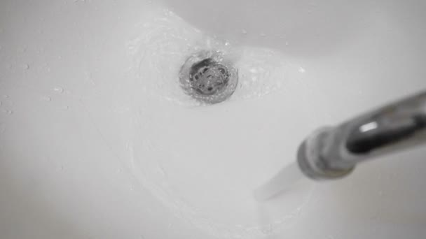 Wasser fließt aus dem Wasserhahn in die Spüle oder das Waschbecken im Bad — Stockvideo