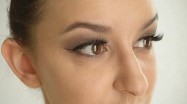 Girlss uzun sahte kirpikleri ve kahverengi gözleri ile karşı karşıya. Vogue makyaj beyaz arka plan üzerinde closeup güzel kadın modeliyle
