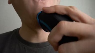 Closeup adam, beyaz arka planda işe gitmeden önce, elektrik döner Razor ile sakal veya inler tıraş