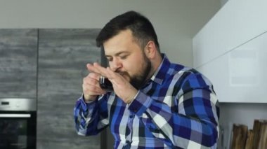 neşeli ve mutlu kalın sakallı adam içecek bir fincan kavrulmuş zemin kahve ve dans modern bir mutfakta yavaş hareket