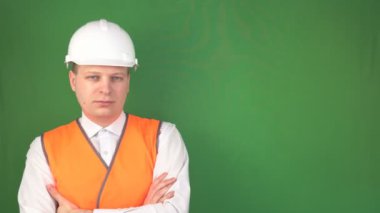 Bir sinyal yelek ve inşaat beyaz kask genç bir adam ayakta ve camreu, background, chromakey, kopya alanı, iş güvenliği ve sağlık bakıyor