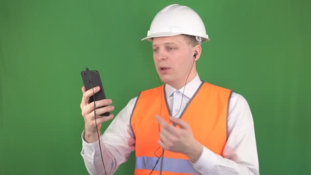 Mladý Kavkazský mužský šéf hovoří na telefonním hovoru ve sluchátkách na staveništi se zákazníkem, pozadím, Chromakey, inženýrem — Stock video