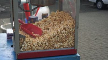 Şehir festivalinde bir konteynerin içinde bir sürü patlamış mısır var. Mısır tatlı karamel incelik hem çocuklar hem de yetişkinler ile popülerdir. Kutunun içinde kırmızı bir spatula var, hangi patlamış mısır çürüyor