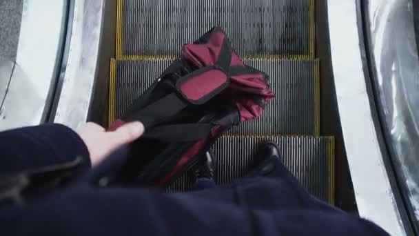 Muž drží v ruce velký pytel a šel dolů na eskalátor a pak se dostane do nějakého předpokladu. Hrozba teroristického útoku. Turisté jezdí s kabelky pro cestování. — Stock video