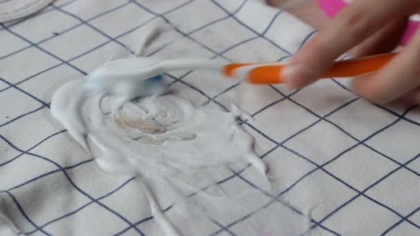 Girl cleans up stains on baby clothes with stain remover, close-up, dry cleaning, domestic — Stock Video
