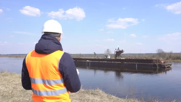 Επιθεωρητής στο γιλέκο σήμα παρακολουθεί την ποιότητα της εργασίας της εκχύλισης της άμμου του ποταμού για την κατασκευή, βιομηχανία — Αρχείο Βίντεο