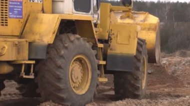 Bobruisk, Beyaz Rusya - 20 Mart 2019: Büyük sarı traktör yükleyici planları ve seviyeleri inşaat için arazi