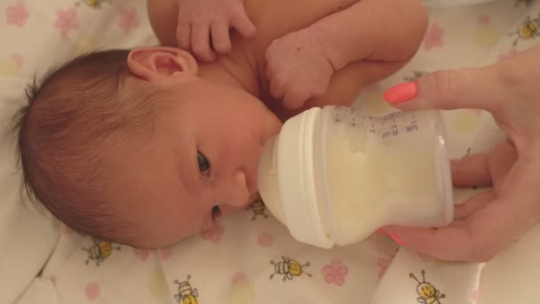 Mother feeds little caucasian girls daughter with a bottle using infant formula, close-up — Stock Video