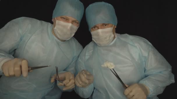 Two surgeon doctors with surgical instruments look into the camera the concept of fear and fear of doctors, medical — Stock Video