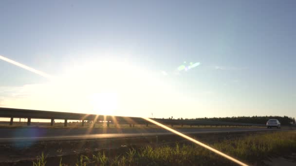 Carros dirigindo na estrada contra o pano de fundo de um pôr do sol, conceito de viagem, espaço de cópia — Vídeo de Stock