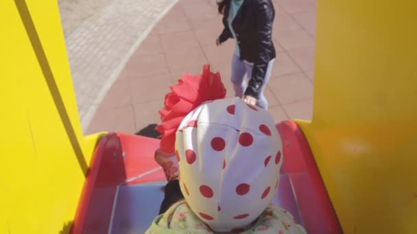 Kaukasische Mutter und ihre verspielte kleine Tochter spielen auf einem bunten, neuen und modernen Spielplatz, reiten einen Hügel hinunter, Aktivität — Stockvideo