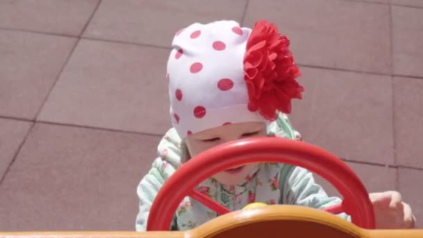Ένα όμορφο μικρό καυκάσιο κορίτσι 3 ετών παίζει σε ένα σύγχρονο νέο και πολύχρωμο παιδική χαρά σε μια ανοιξιάτικη ημέρα, Υπαίθριος, ενεργός — Αρχείο Βίντεο