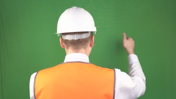 Construtor masculino em um capacete de proteção e colete de sinal mostra comandos com gestos em um canteiro de obras, engenharia de segurança, indústria, hromakey — Vídeo de Stock