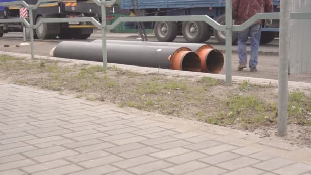 Obras en la ciudad para la sustitución y desmontaje de tuberías para la calefacción principal, grúa eleva nuevas tuberías para la colocación bajo la carretera, equipo — Vídeos de Stock