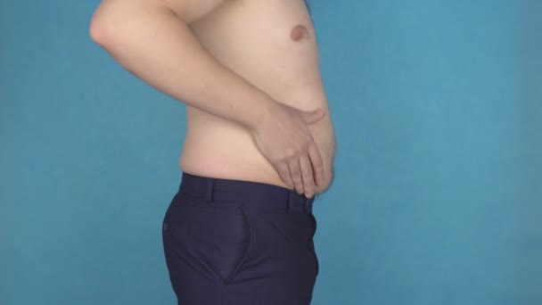 Deux hommes touchent pli gras sur les estomacs de cellulite, surpoids, alimentation malsaine, fond bleu, problème — Video