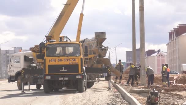 Bobruisk, Wit-Rusland-20 maart 2019: werknemers met een kraan en een cement mixer zetten lichtmasten op een nieuwe weg, de industrie — Stockvideo