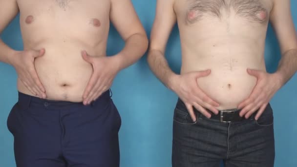 Два человека с жировыми животами касаются морщин на животе, неправильный образ жизни, здоровье, замедленная съемка, избыточный вес — стоковое видео