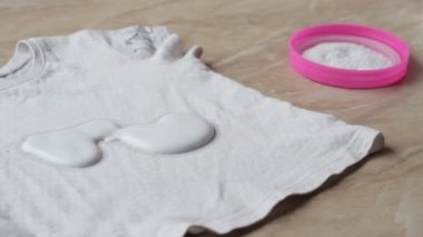 Anne, çocuk giysileri üzerindeki lekeleri şekerlerden leke çıkarıcı ve yıkama tozu yardımı ile temizlemek, yakın çekim, leke giderme, hijyen