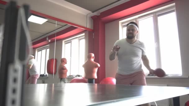 Fett kaukasiska skäggiga man spela bordtennis i ett modernt gym, dumpning övervikt, slow motion — Stockvideo