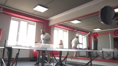 Arkadaşlar sakallı bir adam ve yeni spor salonunda masa tenisi oynayan güzel bir güzel kız, spor ve sağlık, yavaş hareket, simpatico