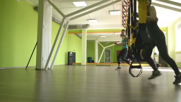 Групповые занятия занимаются девушки и мужчины с тренером на TRX петлях, потеря веса и развитие выносливости, силовые тренировки — стоковое видео