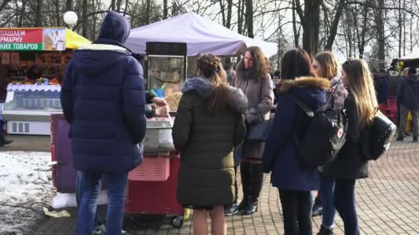 봄 도시 공원에서 카니발 시즌 을 축하하는 동안 청소년들이 벨라루스 보브루스크에서 회전하는 사탕 치실을 지켜보고 있습니다. 공정개최. — 비디오