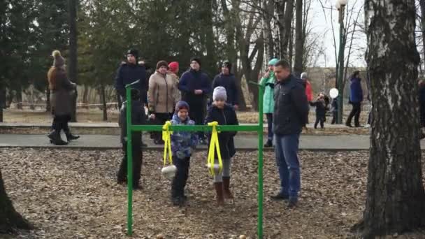 BOBRUISK, BELARUS 03.09.19: La gente celebra la semana de los panqueques en el parque. Los niños juegan con marihuana. Los niños tiran piedras al caldero. La gente disfruta su fin de semana . — Vídeos de Stock