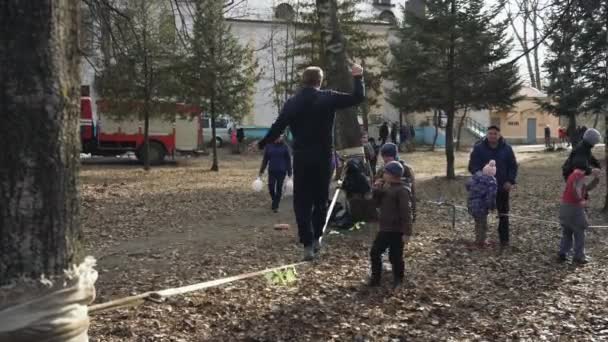 ボブリスク、ベラルーシ03.09.19:ペオポールは春の始まりのお祝いを楽しんでください。男は綱渡りをする。子供たちは休日を楽しむために。子供たちは小さなショーを見ます. — ストック動画