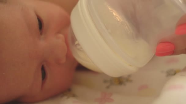 Mãe alimenta meninas caucasianas pequena filha com uma garrafa usando fórmula infantil, close-up — Vídeo de Stock