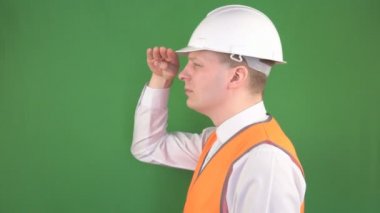 Koruyucu kask ve sinyal yeleği erkek baş baş foreman bir şantiye, yeşil arka plan, hromakey üzerinde mesafe içine bakar