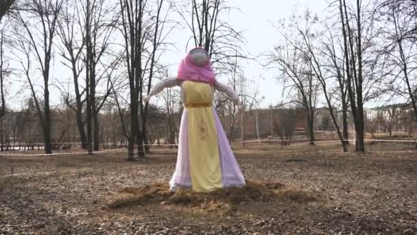 O efigie a lui Maslenitsa este în parc în timpul sărbătorii religioase a Doamnei Untului. O sperietoare umplută de Crepe Week într-o rochie și o batistă roz — Videoclip de stoc