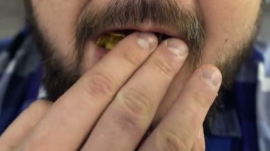 Yakın çekim sakal ve bıyığı olan şişman bir adam ağzına cips sokur. Yüz saçlı büyük bir erkek ağzına net iter. Patates cips yüksek kalori Gıda ile sağlıksız Lifestyle. Risk