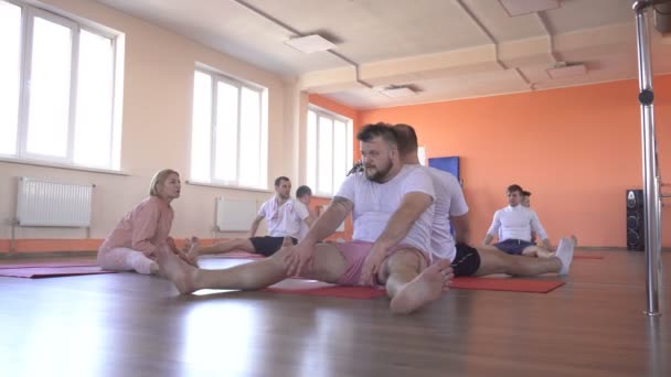 Hermosa instructora caucásica enseña técnicas de yoga en una sesión grupal masculina. fortalecer el músculo y la salud con asanas en yoga, gimnasio moderno, saludable — Vídeo de stock