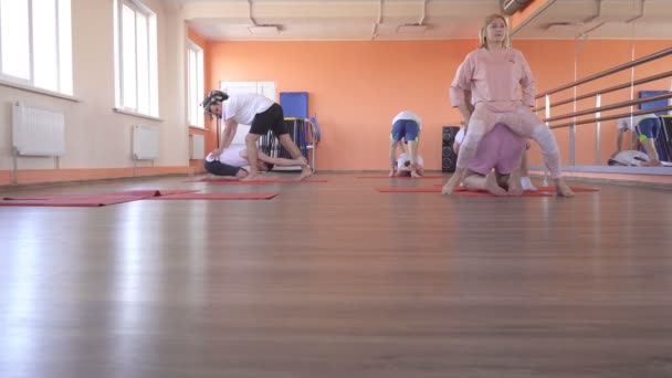 Yoga-Kurse mit einem individuellen Instruktor mit einem schönen kaukasischen Mädchen in einem modernen Fitnesscenter, männliche Freunde, die Yoga machen, um Übergewicht zu reduzieren und Gesundheit und Hauttonus, Muskeln zu fördern — Stockvideo