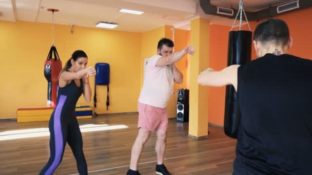 Una ragazza magra e un treno per uomini in sovrappeso fanno schifo. Coach privato con manubri. Esercitazioni individuali di perdita di peso per ragazzo di spessore. Riscaldati prima dell'allenamento di boxe in palestra. Allenamento con istruttore personale in — Video Stock