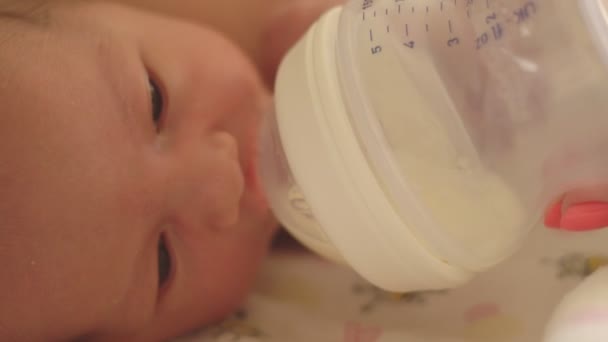 Mãe alimenta meninas caucasianas pequena filha com uma garrafa usando fórmula infantil, close-up — Vídeo de Stock